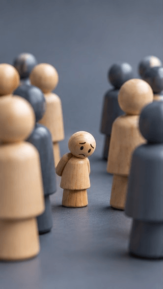 A small worried wooden figure standing among much larger figures
